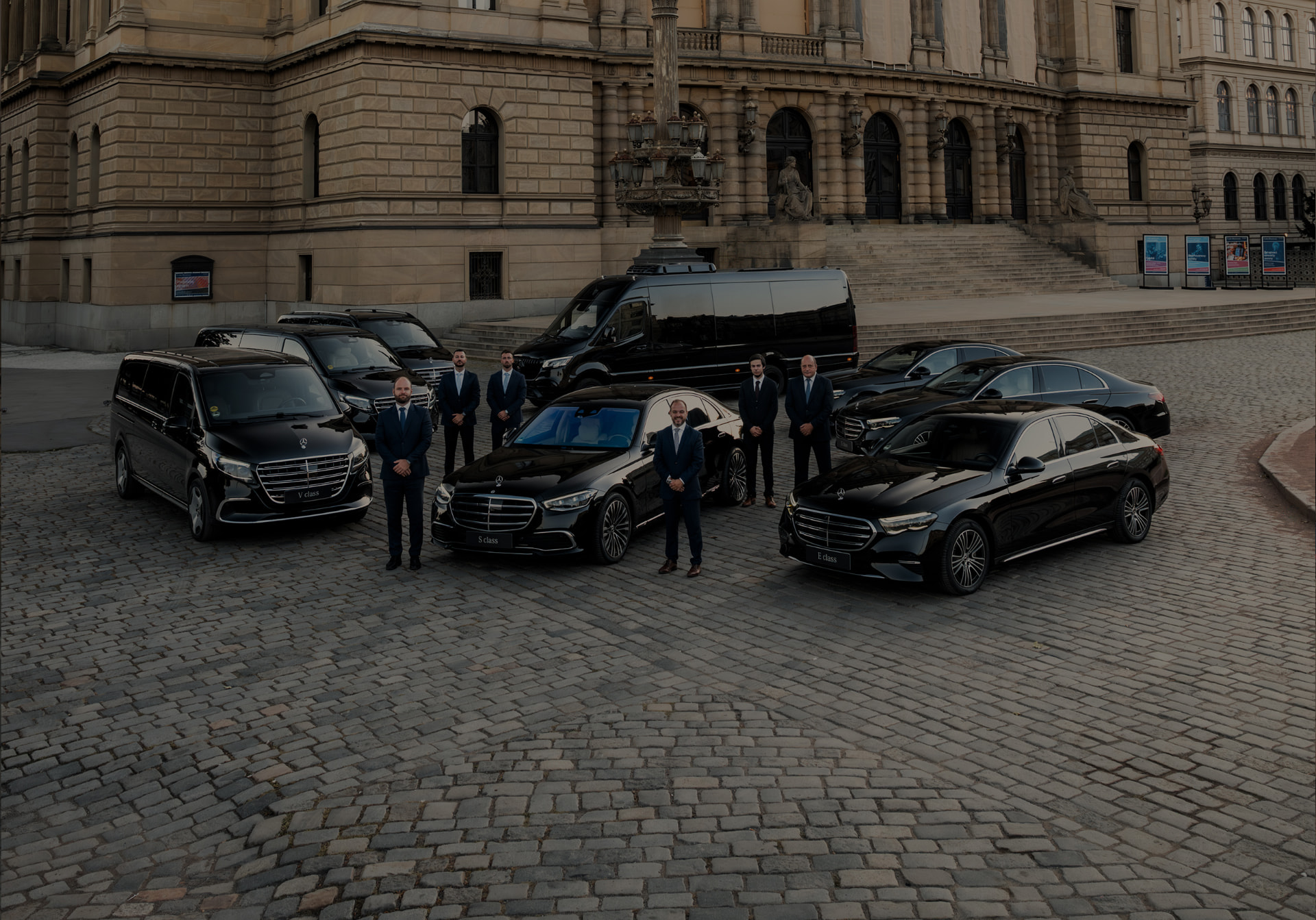 Fleet of black Mercedes-Benz vehicles with chauffeurs in front of the Rudolfinum in Prague